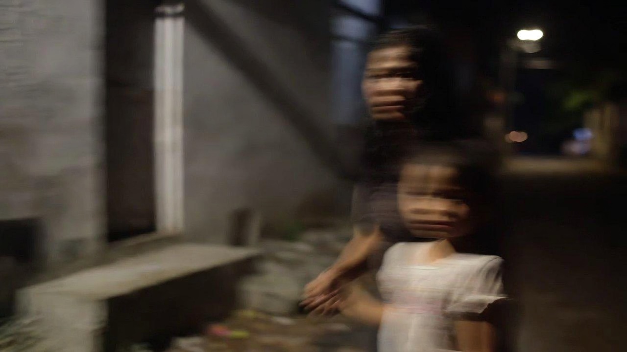 A Filipino mother and her daughter in a dim alley at night, motion-blurred.